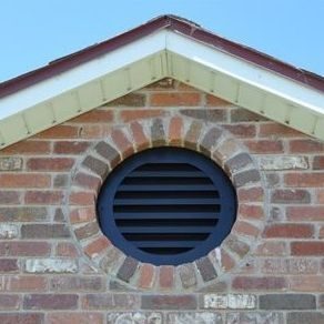 Eye-level view of a metal gable vent with louvers on a house gable