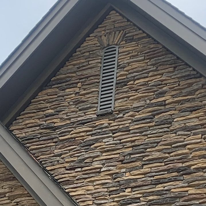 Slim arch top gable vent installed in a stone gable