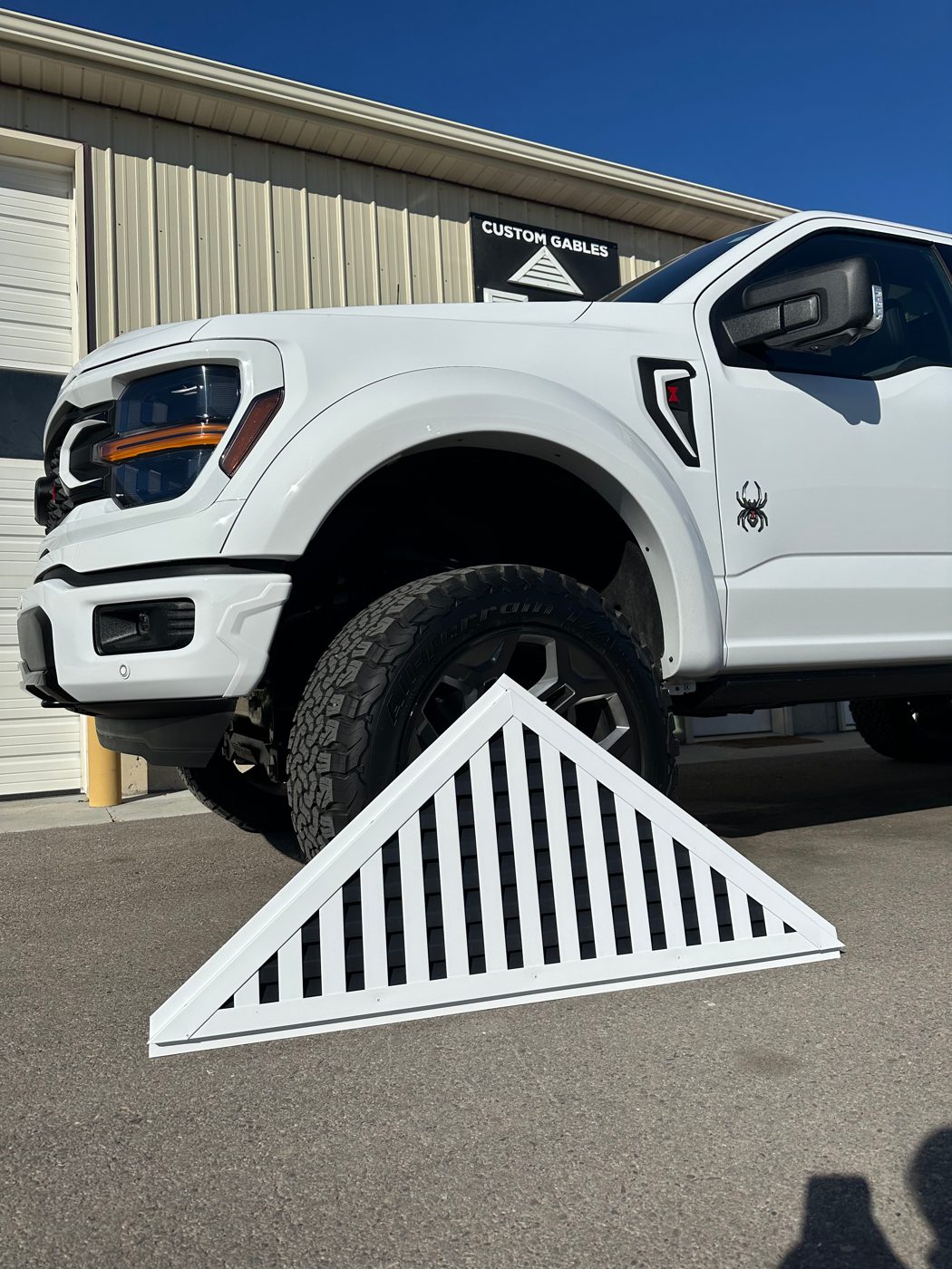 Custom white aluminum triangle gable vent beside a pickup truck