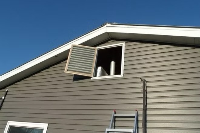 The same hinged gable vent swung open, showing the attic access