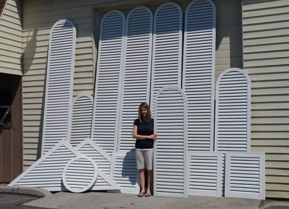 A person standing beside a row of tall custom arch top and rectangle vents, some taller than she is